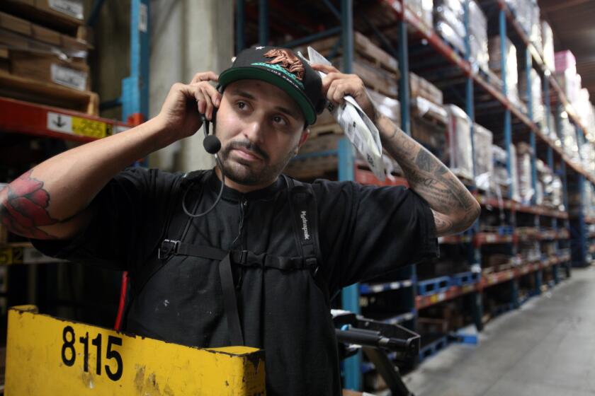 Unified Grocers workers such as Jason Arredondo in Commerce are required to wear headsets through which they are told what to do and how quickly they must do it.