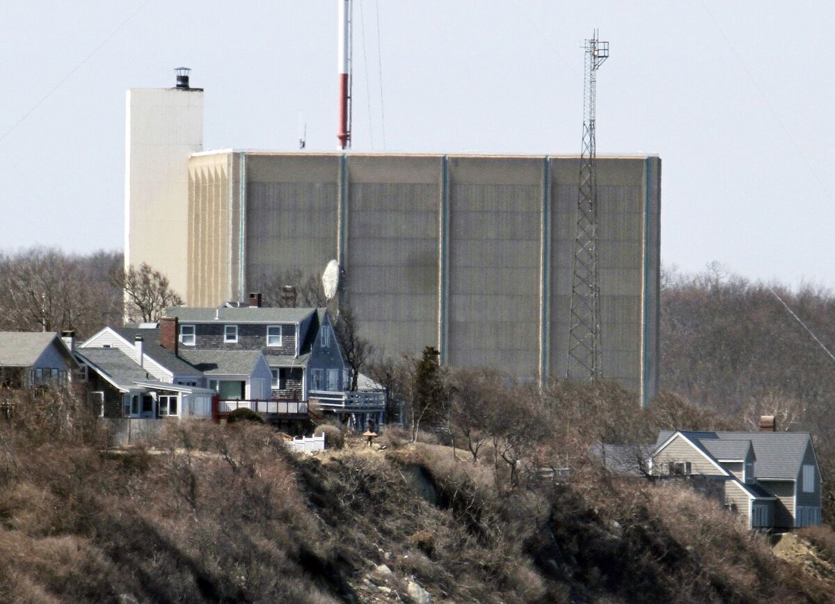 FILE - A portion of the Pilgrim Nuclear Power Station is visible beyond houses along the coast of Cape Cod Bay, in Plymouth, Mass., March 30, 2011. Pilgrim, which closed in 2019, was a boiling water reactor. Water constantly circulated through the reactor vessel and nuclear fuel, converting it to steam to spin the turbine. The water was cooled and recirculated, picking up radioactive contamination. (AP Photo/Steven Senne, File)