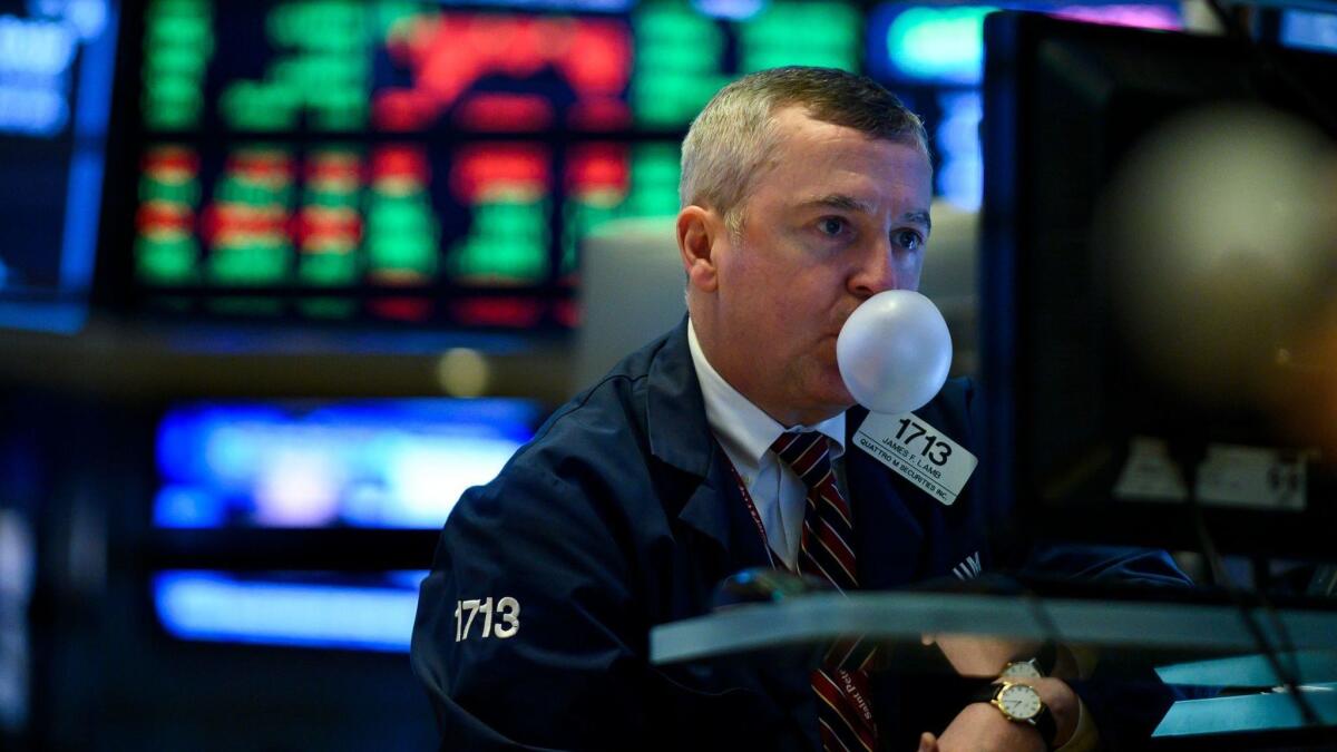 A trader chewing gum blows a bubble while working on the floor of the New York Stock Exchange.