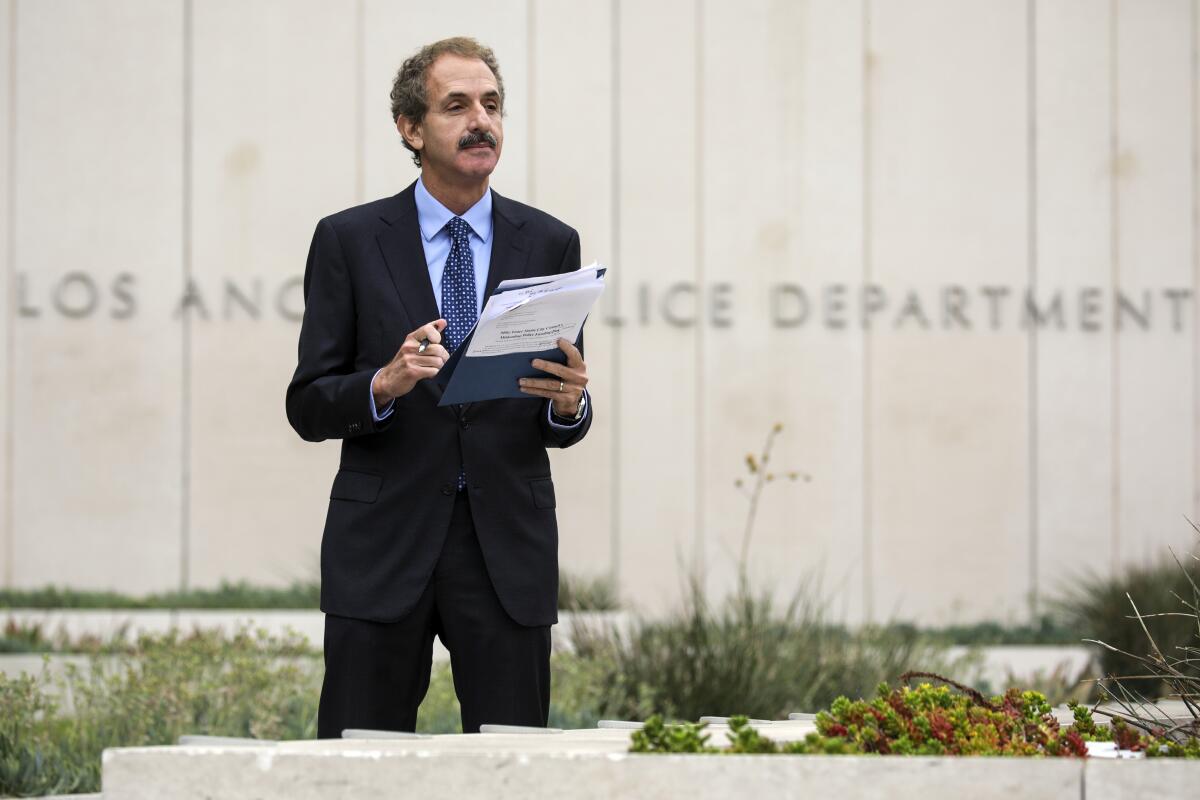 Mike Feuer holds papers outside LAPD headquarters.