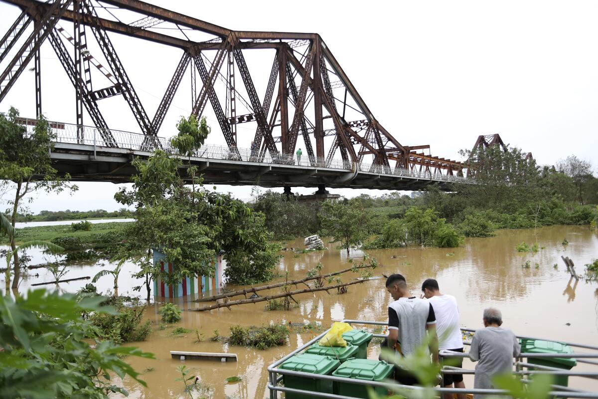 People watch the flooded Red river next to iconic Long Bien bridge, following Typhoon Yagi in Hanoi, Vietnam.