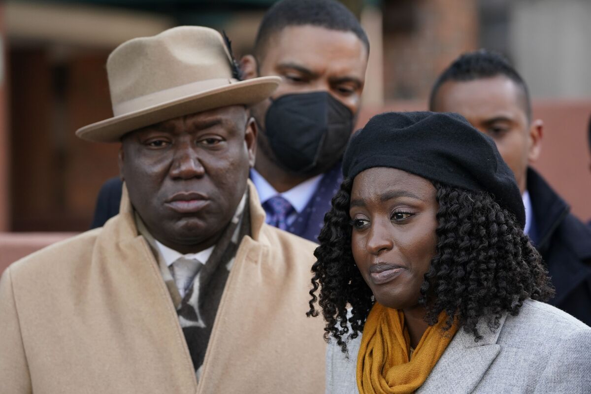 Attorney Ben Crump, left, looks on as Fatiah Touray, who has family that was killed in a building fire, speaks to reporters at a news conference in the Bronx borough of New York, Tuesday, Feb. 8, 2022. Several families whose loved ones died while trying to escape a smoked-filled Bronx apartment building sued the building owners Tuesday, alleging safety violations that led to the wrongful deaths of 17 people, including eight children. (AP Photo/Seth Wenig)