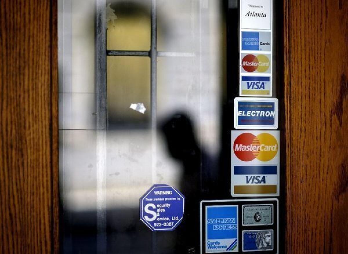 Credit card logos on a downtown Atlanta storefront as a pedestrian passes in July.