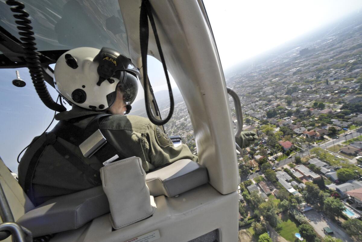 In this file photo from 2009, Glendale Police Officer Mike Woolner searches for a suspect while aboard a helicopter owned by the Burbank and Glendale police departments.