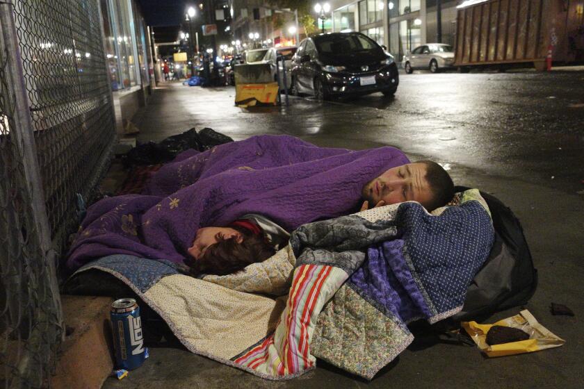 FILE - In this Sept. 18, 2017, file photo, two people sleep on a street in downtown Portland, Ore. Voters in metropolitan Portland will be asked Tuesday, May 19, 2020 to approve taxes on personal income and business profits that would raise $2.5 billion over a decade to fight homelessness even as Oregon grapples with the coronavirus pandemic and its worst recession in decades. (AP Photo/Ted S. Warren, File)