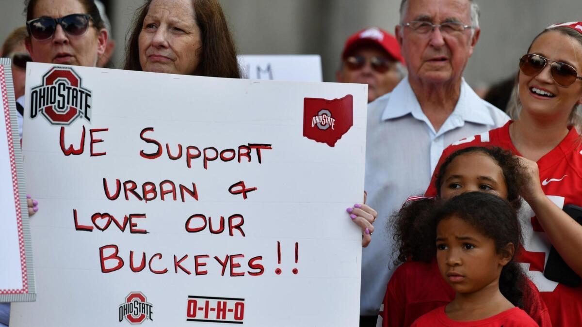 Supporters of Ohio State head football coach Urban Meyer hold signs at a rally at Ohio State University.