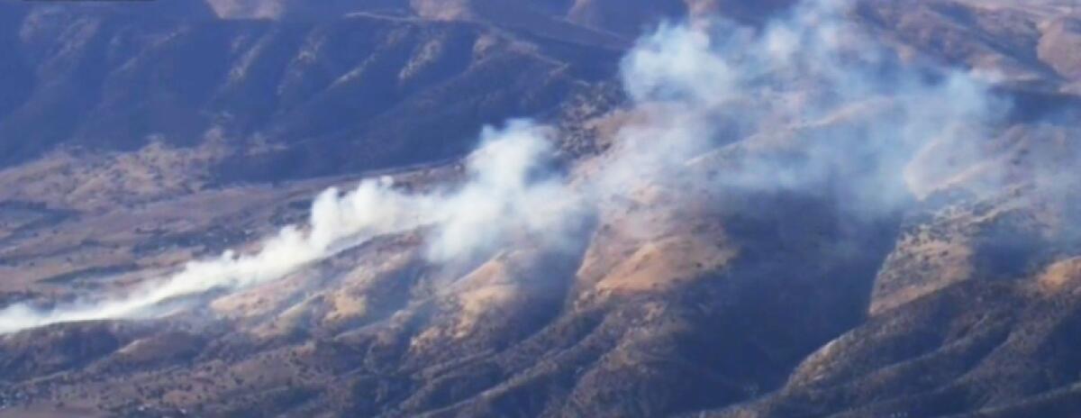 Aerial view of foothills with smoke rising above.