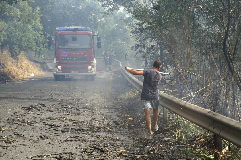 A volunteer helps controlling fire in Fuscaldo, near Cosenza, Calabria, Italy, Wednesday, Aug. 11, 2021, as many wildfires continue plaguing the southern regions of Italy. Sicily, Sardinia, Calabria and also central Italy, where temperatures are expected to reach record hight, were badly hit by wildfires. Climate scientists say there is little doubt that climate change from the burning of coal, oil and natural gas is driving extreme events, such as heat waves, droughts, wildfires, floods and storms. (Luigi Salsini/LaPresse via AP)