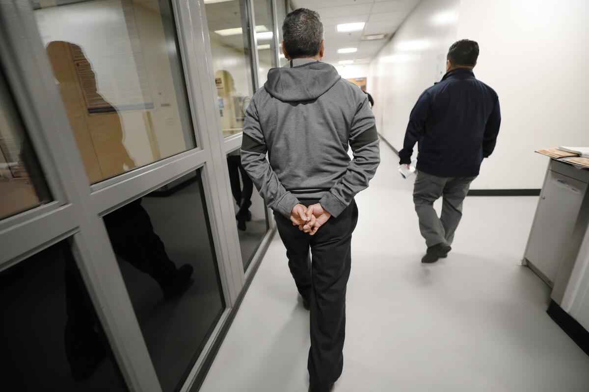 Marcos Correa, center, is escorted by officers at the Enforcement and Removal Operations processing center in downtown Los Angeles after being apprehended by ICE agents.