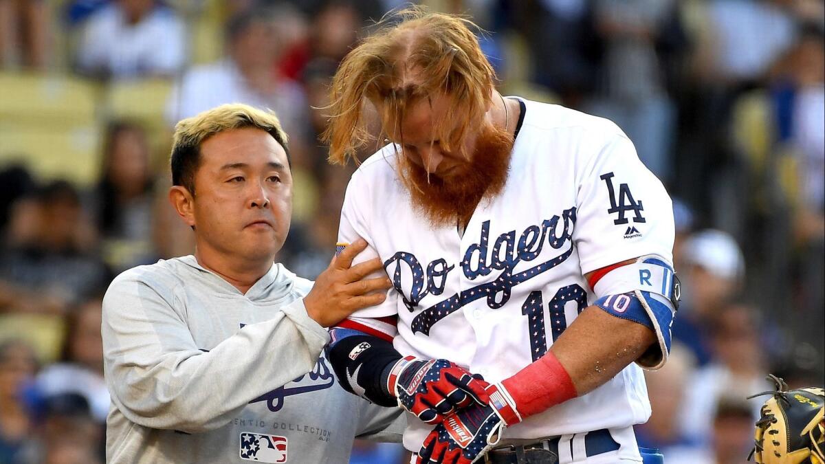 Dodgers' Justin Turner is tended to by assistant athletic trainer Yosuke Nakajima after being hit in the head by a pitch from Pittsburgh Pirates pitcher Tyler Glasnow in the fifth inning on Wednesday.