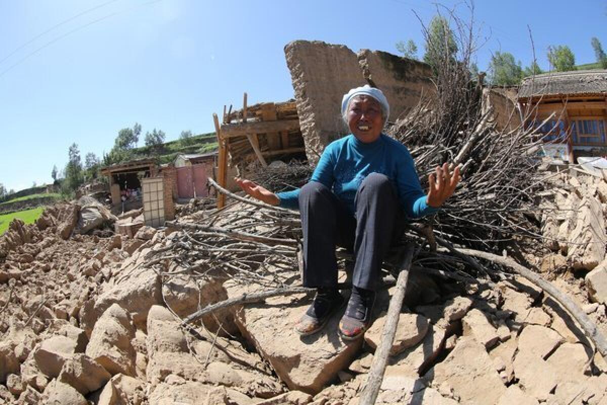 A distraught resident sits outside her collapsed house in the Dingxi township of Hetuo in northwest China's Gansu province.