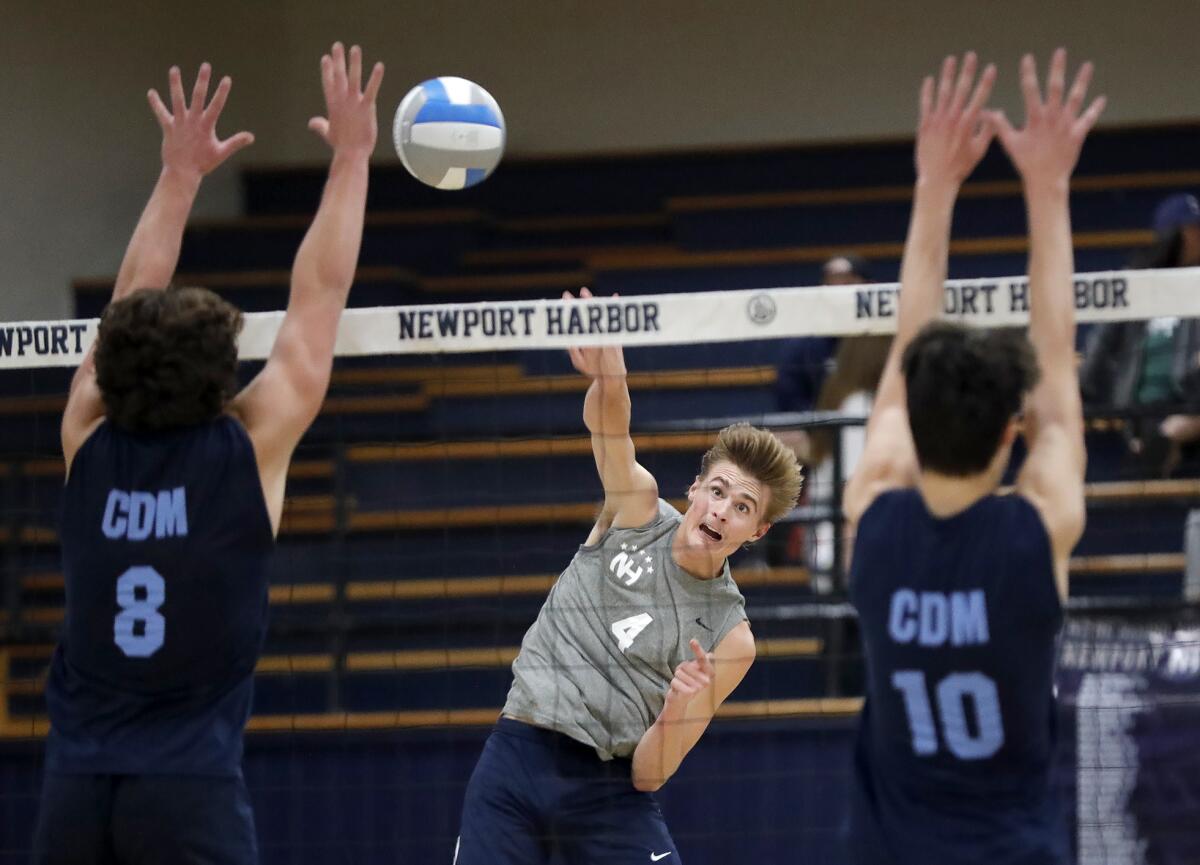 Newport Harbor's Luca Curci (4) hits a ball past Corona del Mar's Reid McMullen (8) and Cade Alacano (10) on Friday.