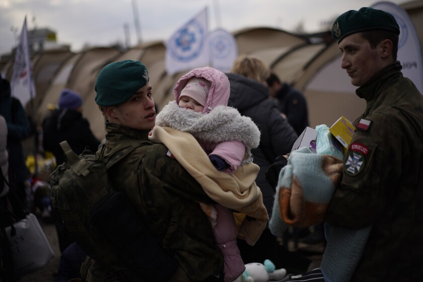 A Polish soldier holds a baby as refugees fleeing war in neighboring Ukraine arrive at the Medyka crossing border, Poland, Thursday, March 10, 2022. (AP Photo/Daniel Cole)