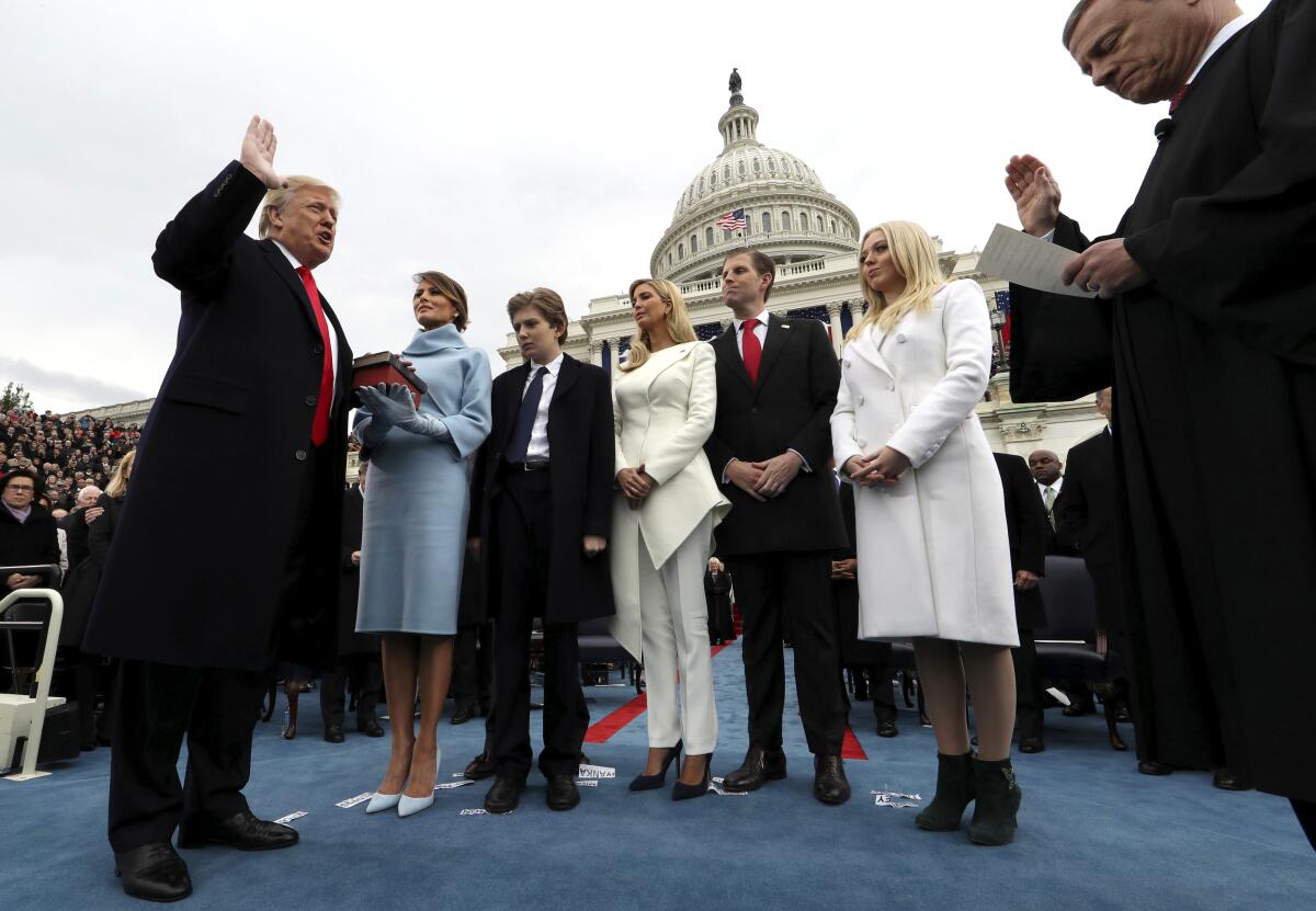 Then-President Trump takes the oath of office at his inauguration outside the U.S. Capitol while his family looks on.