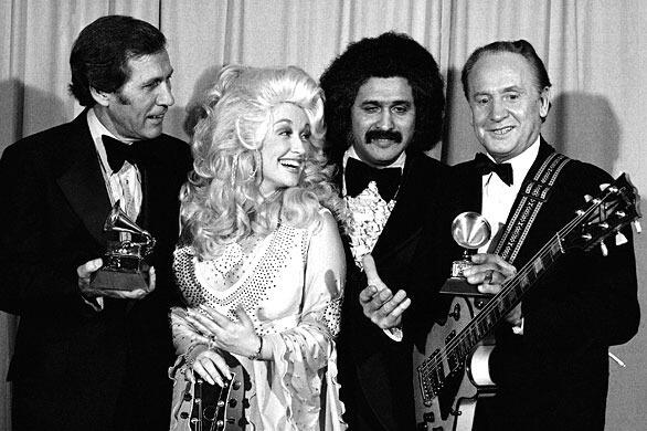 FILE - In this Feb. 19, 1977 file photo, Les Paul, right, and Chet Atkins, left, are presented Grammies by Dolly Parton and Freddie Fender, second from right, at 19th annual Grammy Awards in Los Angeles. Paul, 94, the guitarist and inventor who changed the course of music with the electric guitar and multitrack recording and had a string of hits, died, Thursday, Aug. 13, 2009 in White Plains, N.Y., according to Gibson Guitar. (AP Photo/George Brich, file)
