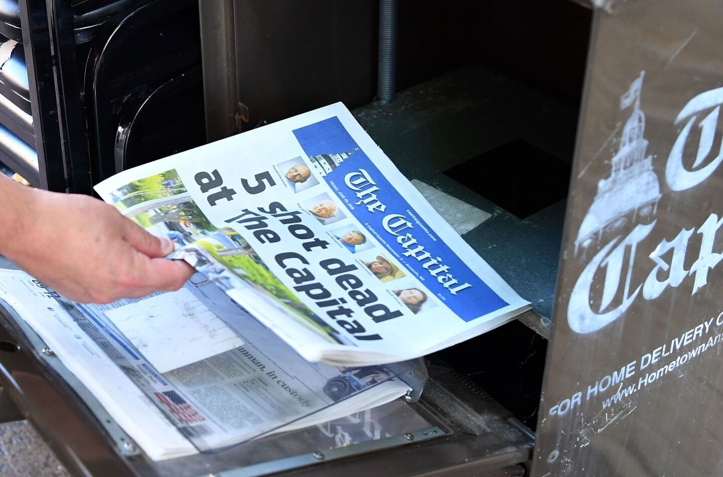 A resident buys a copy of the Capital newspaper in Annapolis, Md., a day after five journalists were shot dead in the newsroom.