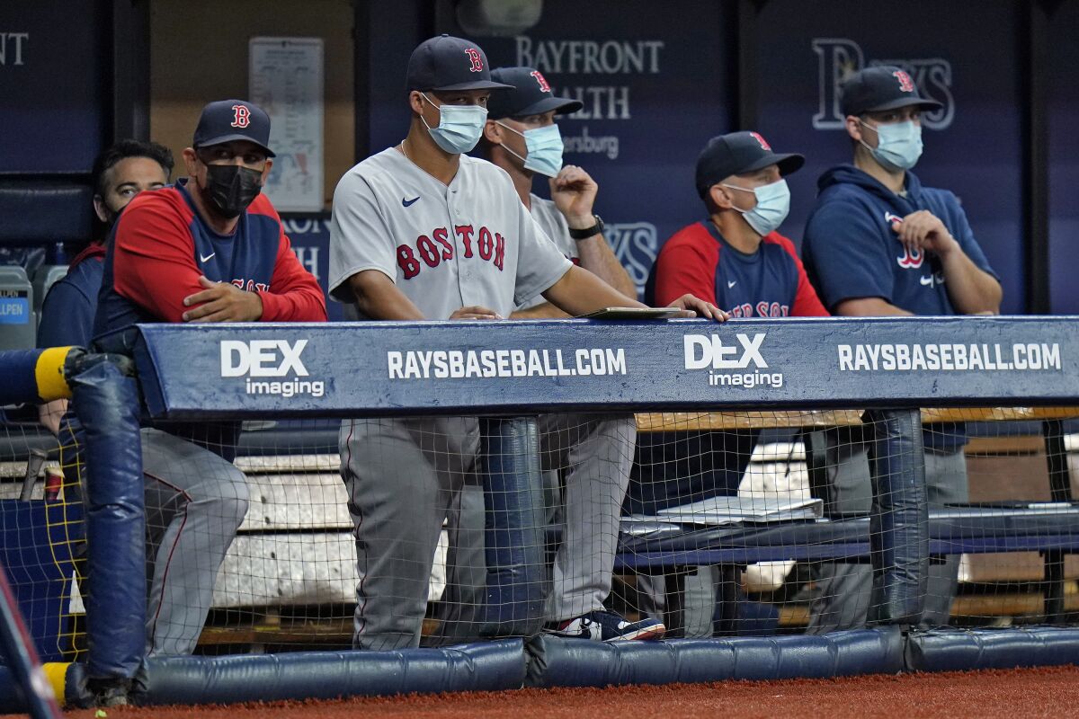 FILE - Boston Red Sox manager Alex Cora, left, and other members of the coaching staff wear protective masks during the fourth inning of a baseball game against the Tampa Bay Rays on Monday, Aug. 30, 2021, in St. Petersburg, Fla. Major League Baseball is dropping regular COVID-19 testing for all but symptomatic individuals while maintaining an abiity to move games if the public health situation in an area deteriorates. MLB and the players’ association finalized their 2022 COVID protocols on Tuesday, March 15, 2022, as it easing pandemic restrictions five days after reaching a collective bargaining agreement. (AP Photo/Chris O'Meara, File)