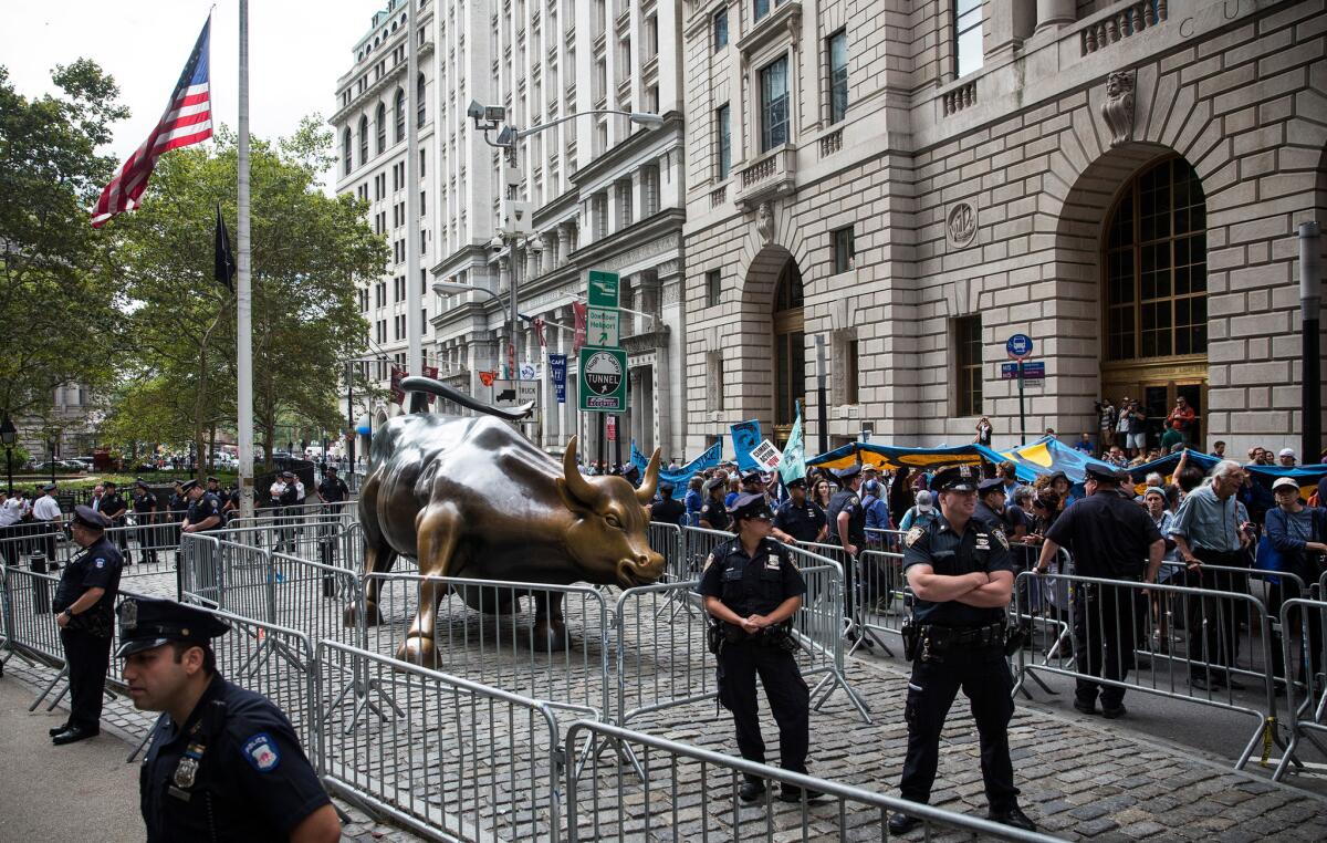 Police officers protect the Wall Street Bull statue during a sit in Monday by protesters calling for massive economic and political changes to curb the effects of global warming.
