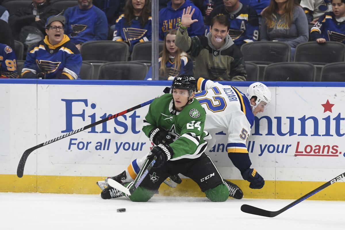 Dallas Stars' Roope Hintz (24) fights for the puck against St. Louis Blues' Noel Acciari (52) during the first period of an NHL hockey game Monday, Nov. 28, 2022, in St. Louis. (AP Photo/Michael Thomas)