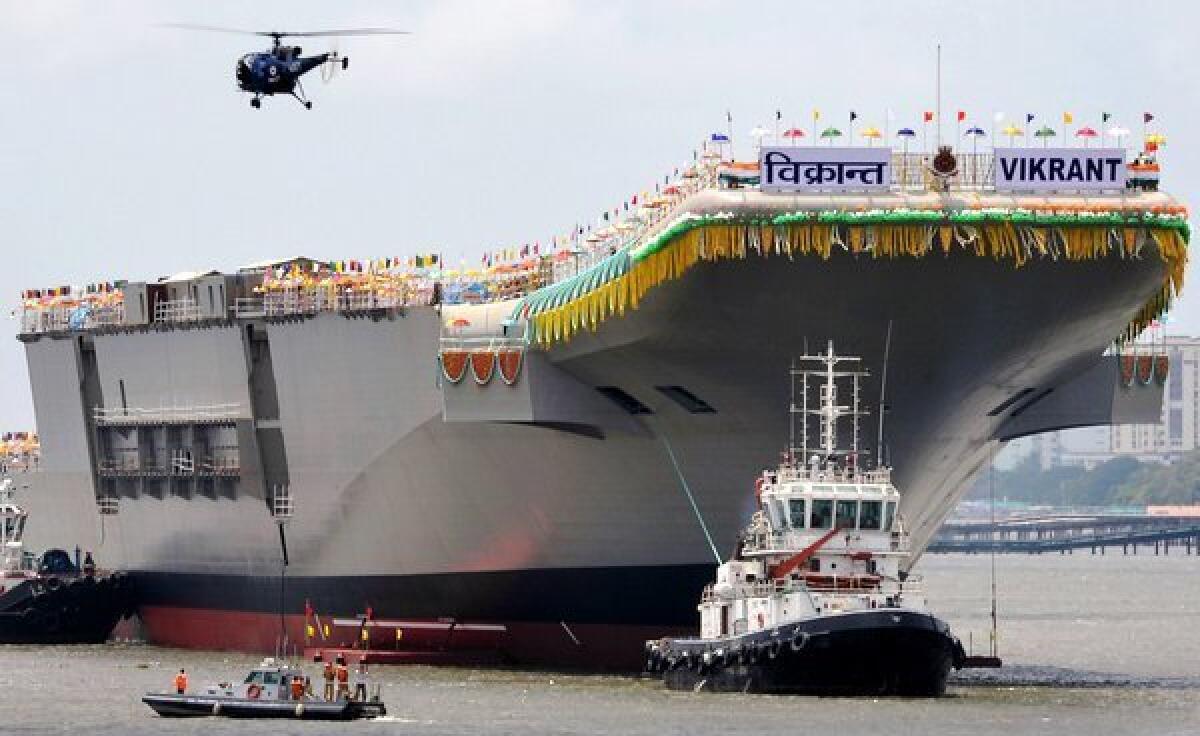 Tugboats guide the domestically built aircraft carrier INS Vikrant as it leaves the Cochin Shipyard after the launch ceremony in Kochi, India, on Monday.