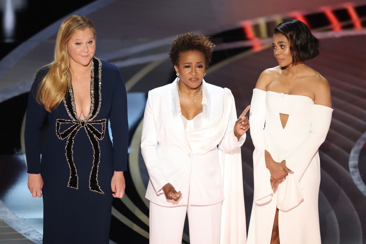 Three women standing on a stage in formalwear