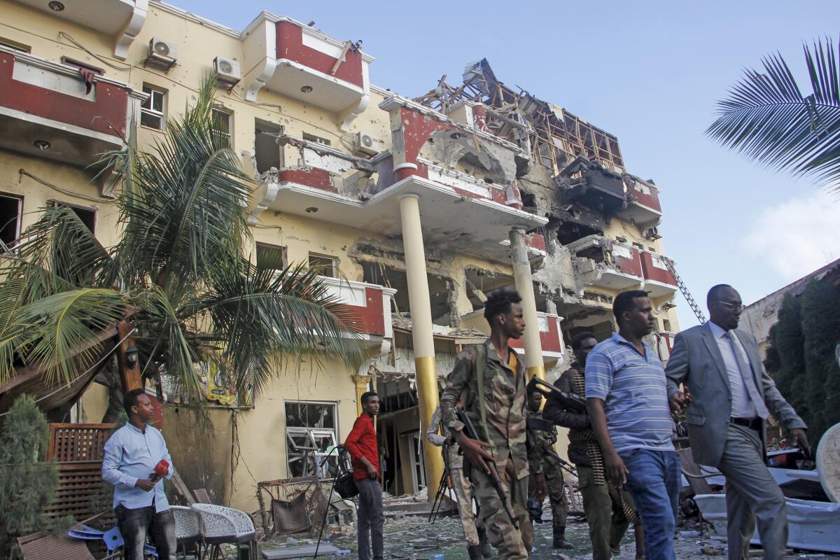 Security forces and others walk in front of the damaged Hayat Hotel in the capital Mogadishu, Somalia Sunday, Aug. 21, 2022. Somali authorities on Sunday ended a deadly attack in which at least 20 people were killed and many others wounded when gunmen from the Islamic extremist group al-Shabab, which has ties with al-Qaida, stormed the Hayat Hotel in the capital on Friday evening. (AP Photo/Farah Abdi Warsameh)