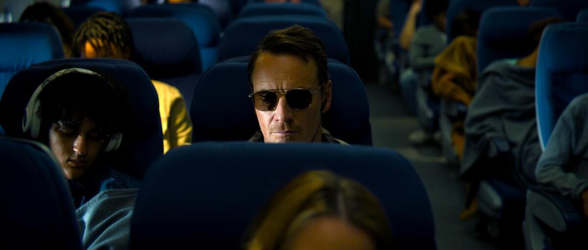 A man in shades flies on an airplane.