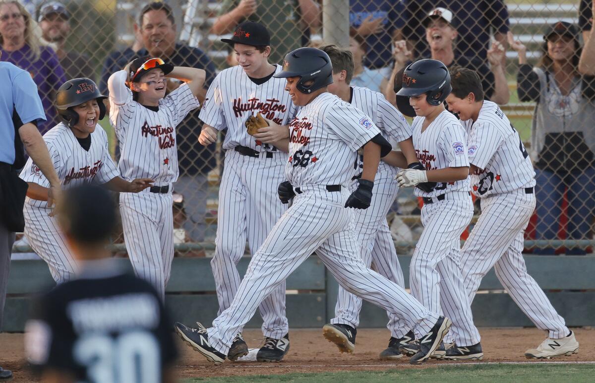 Huntington Valley's Justin Garcia steps onto home plate surrounded by teammates after hitting a walk-off home run.