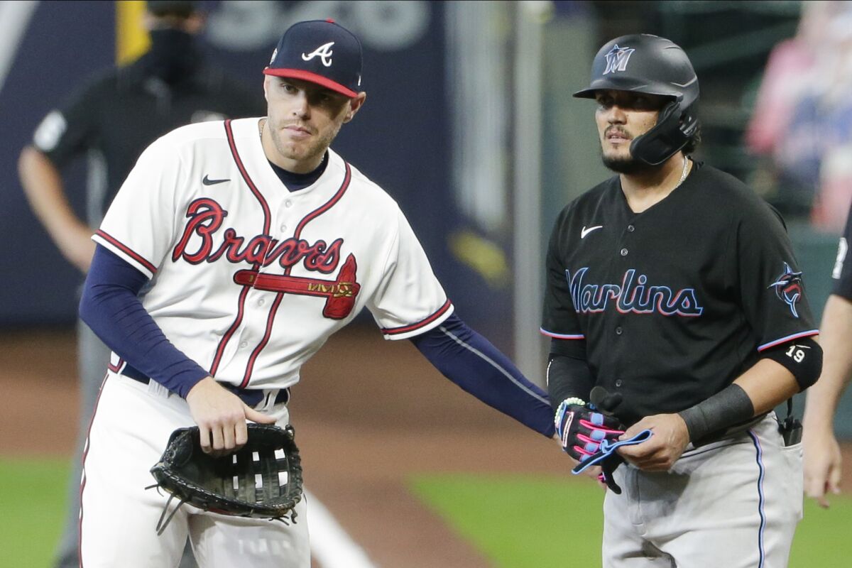 Atlanta Braves first baseman Freddie Freeman, left, taps Miami Marlins' Miguel Rojas, right, on the hip after Rojas was hit by a pitch during the eighth inning in Game 1 of a baseball National League Division Series Tuesday, Oct. 6, 2020, in Houston. The Braves won 9-5. (AP Photo/Michael Wyke)