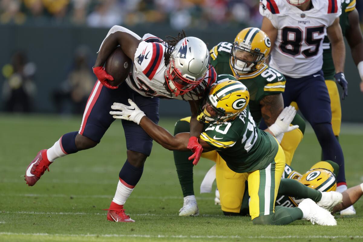 New England Patriots running back Rhamondre Stevenson, right, is tackled by Green Bay Packers safety Rudy Ford (20) during the first half of an NFL football game, Sunday, Oct. 2, 2022, in Green Bay, Wis. (AP Photo/Matt Ludtke)
