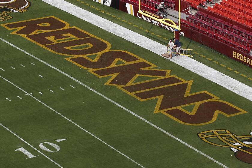 Groundskeepers prepare the end zone for an NFL preseason game between the Washington and New England. The University of Minnesota says it is working with the Vikings to keep the Redskins' controversial name from being used when the two teams play on campus in November.