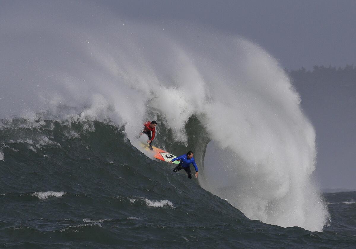 Ken Collins, left, and Chris Bertish surf a giant wave during the second heat of the Mavericks surfing contest Friday.