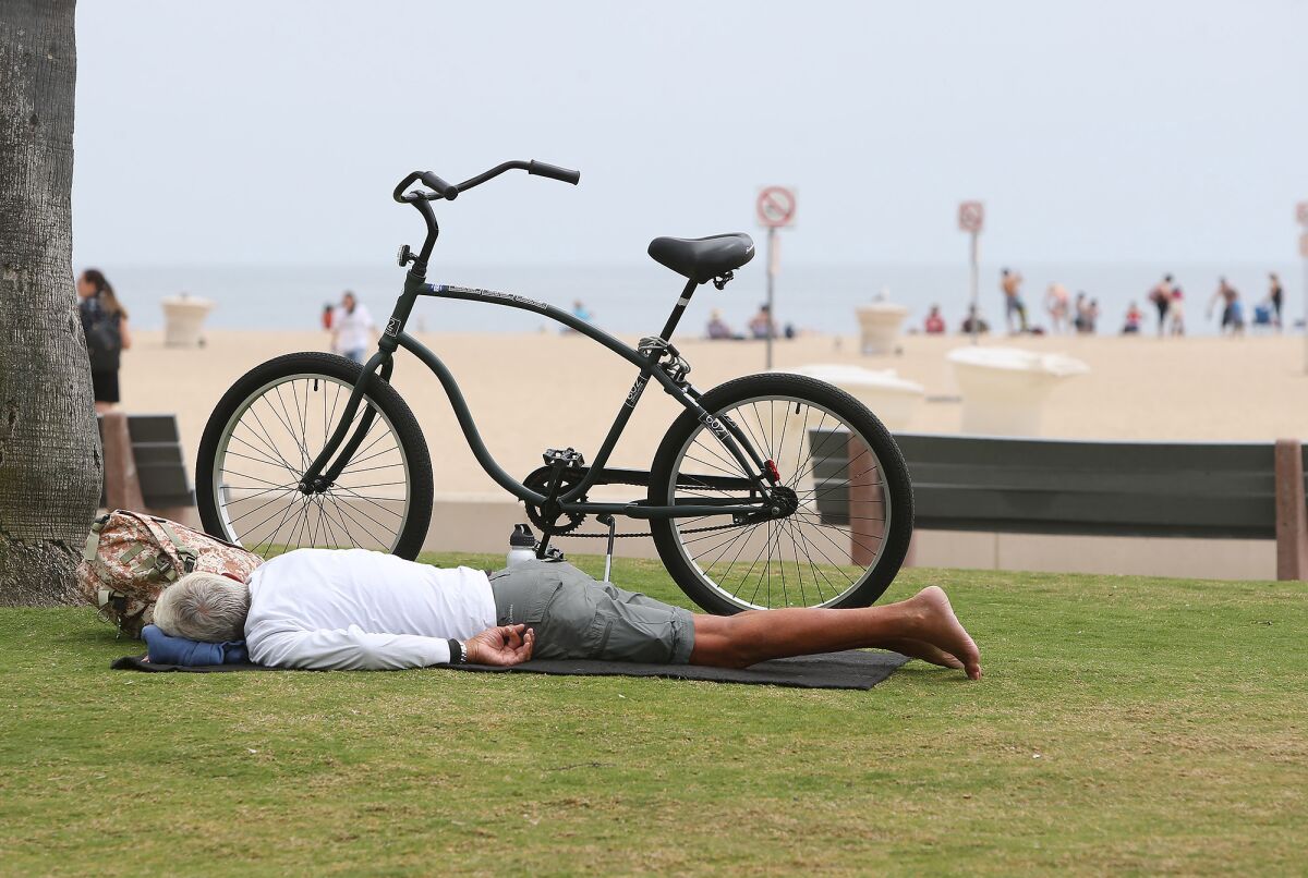 Beachgoer takes a nap on the grass at Corona del Mar State Beach in Newport Beach on Thursday.