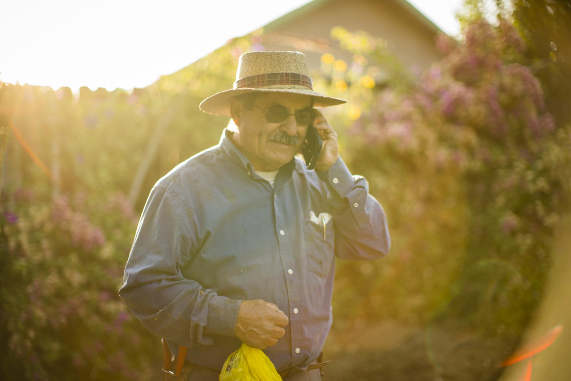 A man holds a cellphone up to left ear outdoors.