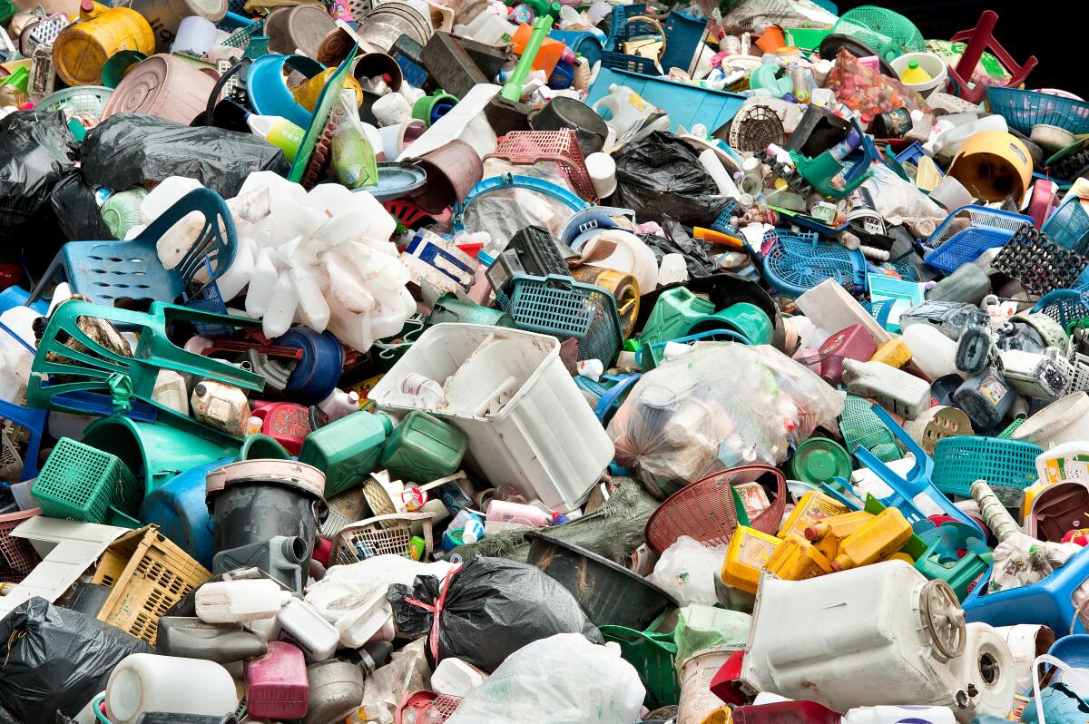 A large pile of plastic waste is shown, including bottles, chairs and containers.