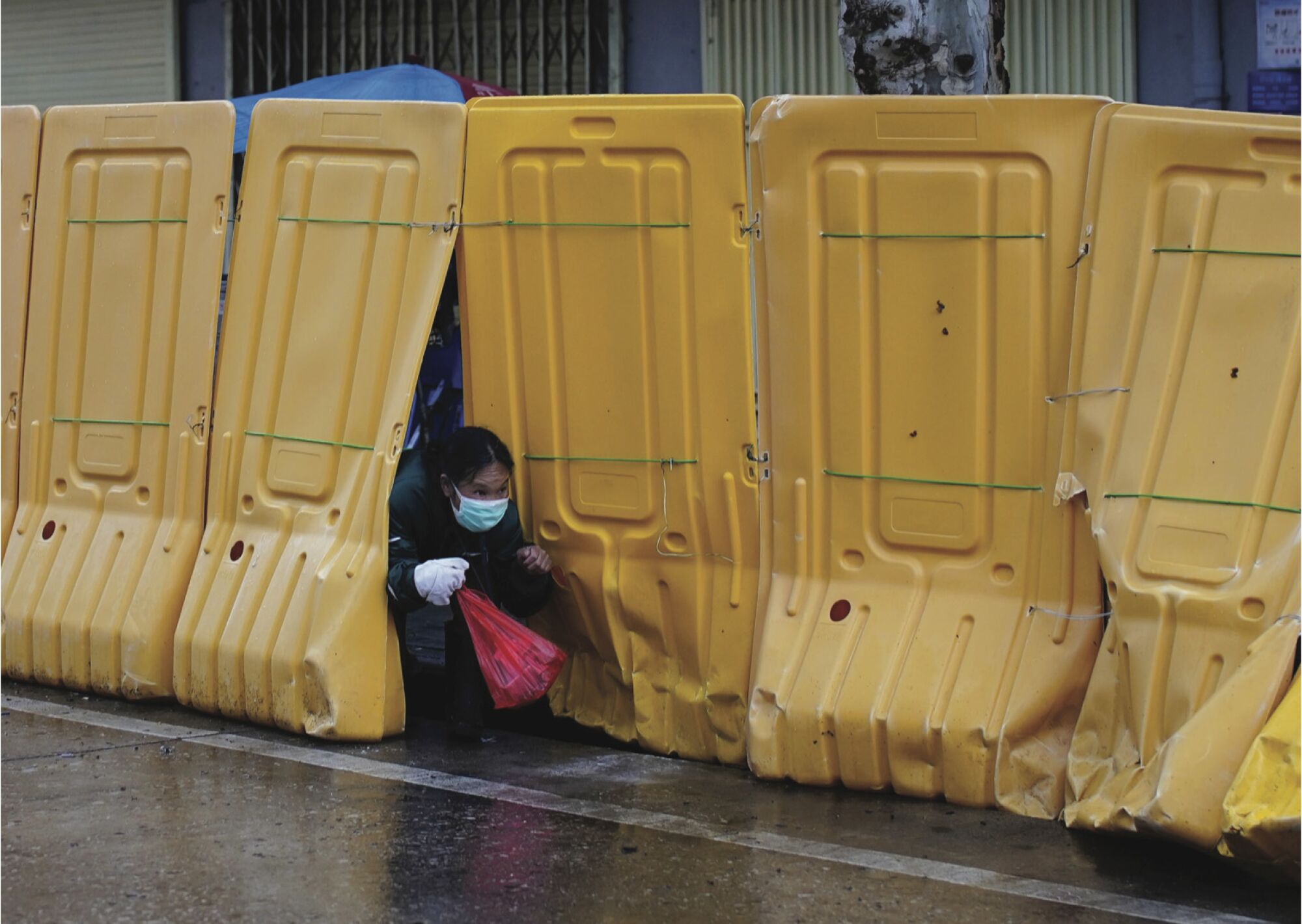 A woman wearing a face mask slips through barriers.
