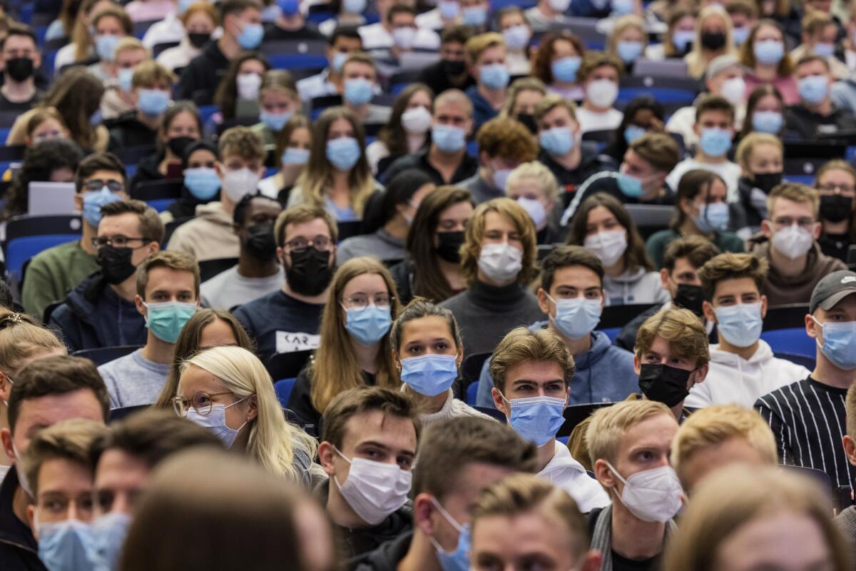 Students sit close to one another while wearing masks