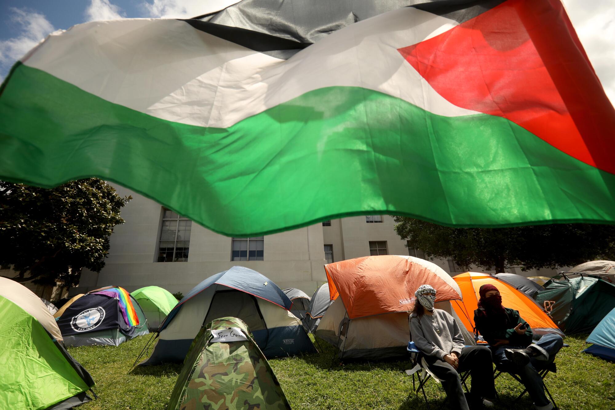 A Palestinian flag flies over tents at UC Berkeley.
