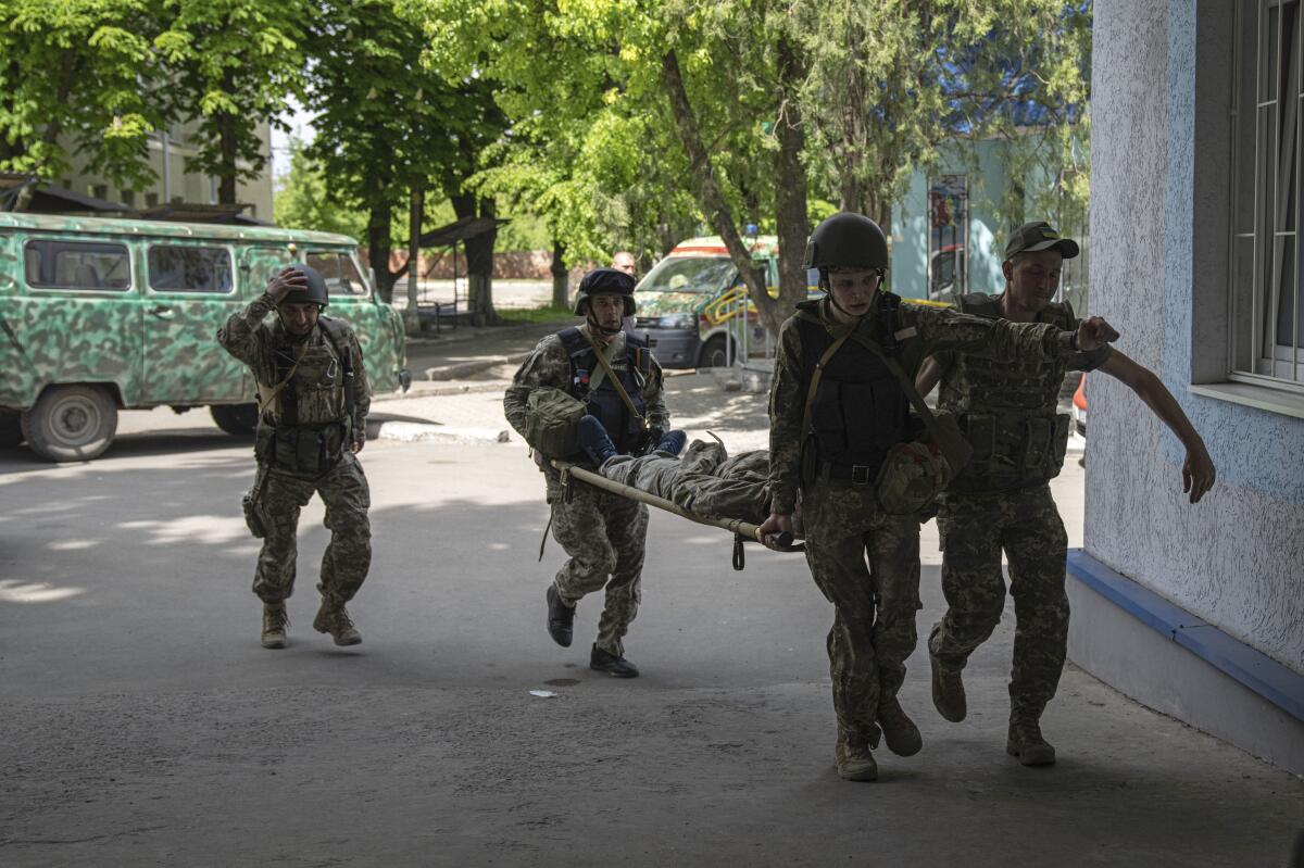 Ukrainian servicemen carry an injured comrade on A stretcher to the hospital after an attack by Russian forces in Donetsk region, Ukraine, on Monday, May 9, 2022.(AP Photo/Evgeniy Maloletka)