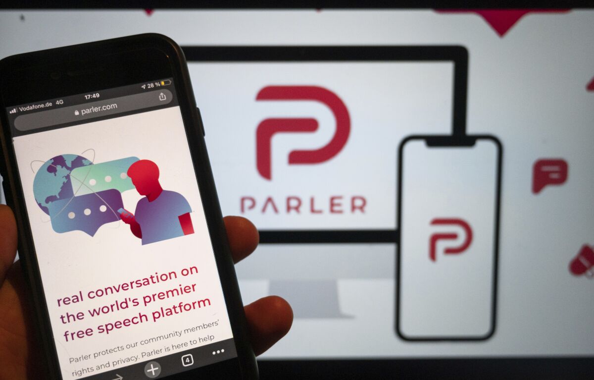 The website of the social media platform Parler is displayed in Berlin, Jan. 10, 2021. The platform's logo is on a screen in the background. The conservative-friendly social network Parler was booted off the internet Monday, Jan. 11, over ties to last week's siege on the U.S. Capitol, but not before hackers made off with an archive of its posts, including any that might have helped organize or document the riot. (Christophe Gateau/dpa via AP)