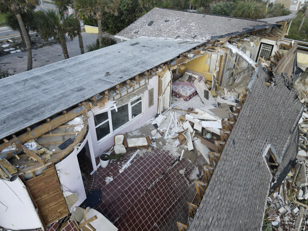 A bed and chairs are seen inside a home that half collapsed after the sand supporting it was swept away, following the passage of Hurricane Nicole, Saturday, Nov. 12, 2022, in Wilbur-By-The-Sea, Fla. (AP Photo/Rebecca Blackwell)