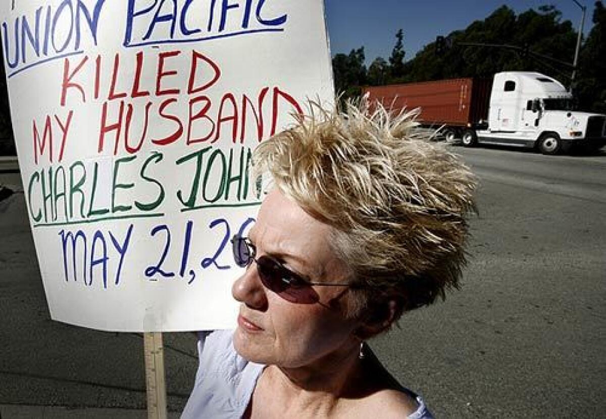 Pat Johnson carries a sign outside the Union Pacific rail yard in Wilmington. Pat's husband, Chuck, a Union Pacific employee, had a heart attack and fell from a platform in 2007. He died on the asphalt. Johnson believes something else went wrong.