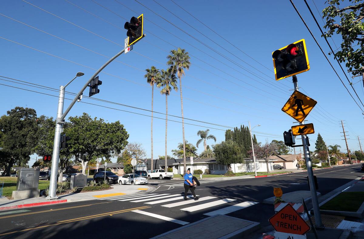 A pedestrian uses a High-Intensity Activated CrossWalK (HAWK) signal to cross Costa Mesa's Wilson Street on Friday. 