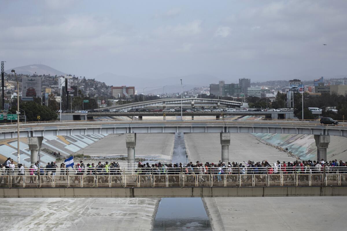 Central American migrants in Tijuana walk toward the U.S. border to request asylum.