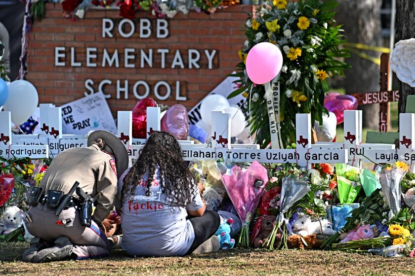 Uvalde, Texas May 26, 2022- A police officer comforts family members at a memorial outside Rob Elementary School in Uvalde, Texas. Nineteen students and two teachers died when a gunman opened fire in a classroom Tuesday. (Wally Skalij/Los Angeles Times)