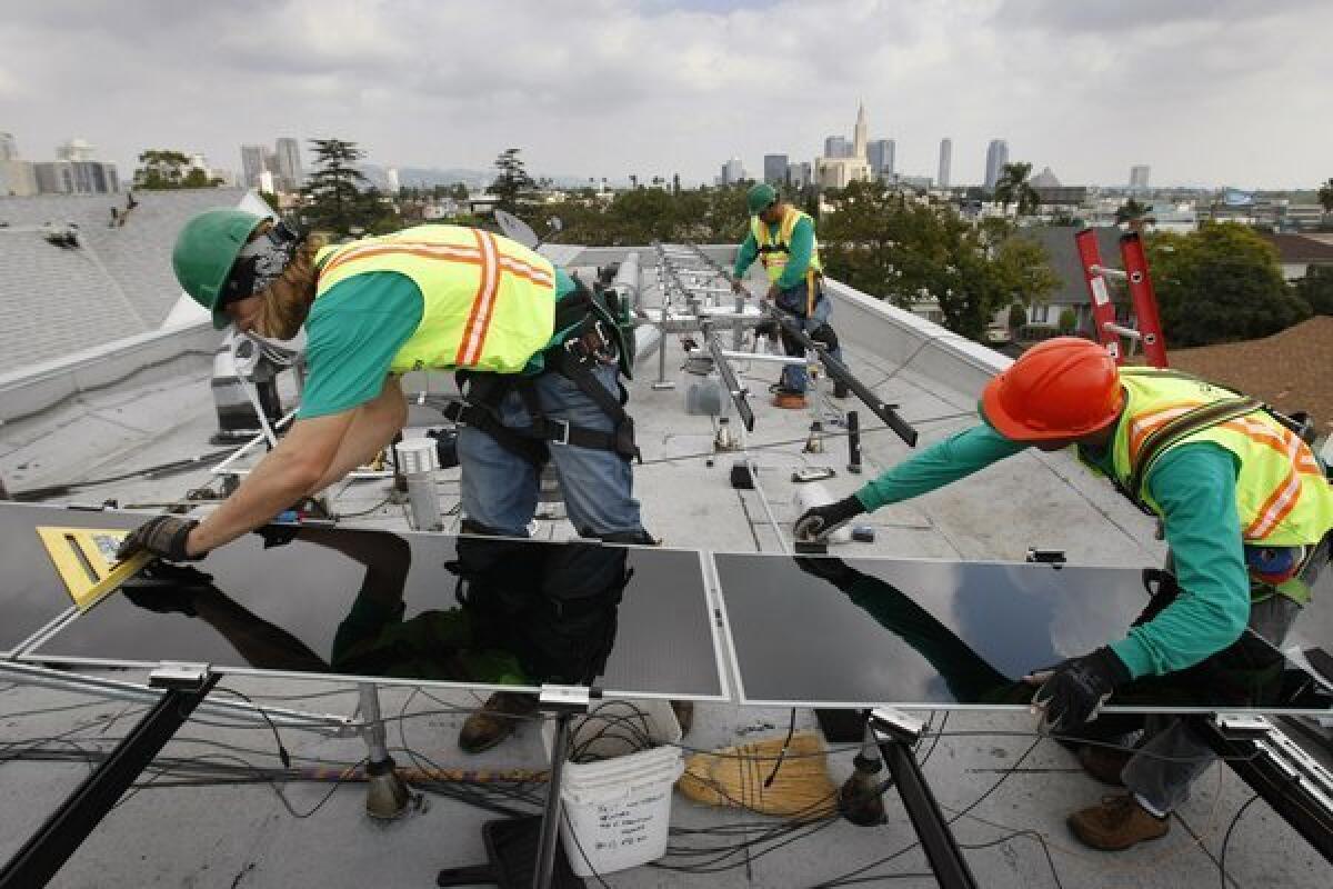 SolarCity installers work on a Los Angeles property. The company said it expects its shares to price at $13 to $15 apiece in its initial public offering.