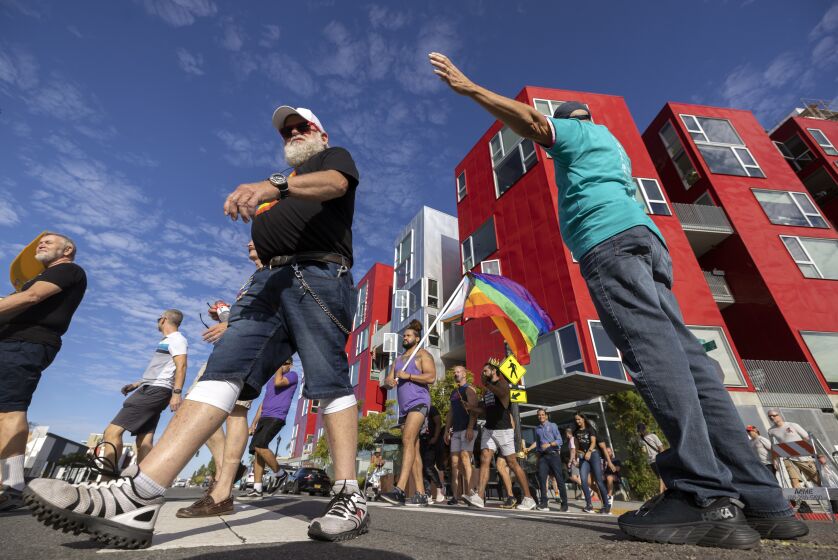 Volunteer Frank DeLuise, right, stops traffic as groups participating in the 33rd annual AIDS Walk & Run San Diego, a fundraising event for HIV service and prevention organizations, cross University Avenue at Centre Street as they begin their walk in San Diego on Saturday, September 24, 2022.