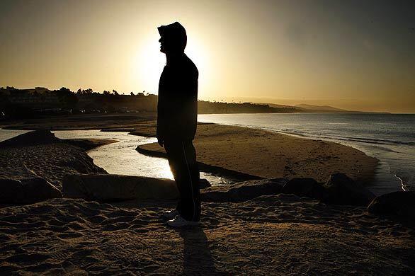The sunrise casts a glow over Dana Point resident Neal Mofhitz on Doheny State Beach, where a 25,000-gallon raw sewage spill on Friday has kept the shoreline closed.