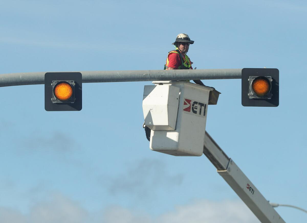 A Caltrans worker begins a project to add flashing overhead lights above a crosswalk to enhance pedestrian safety.
