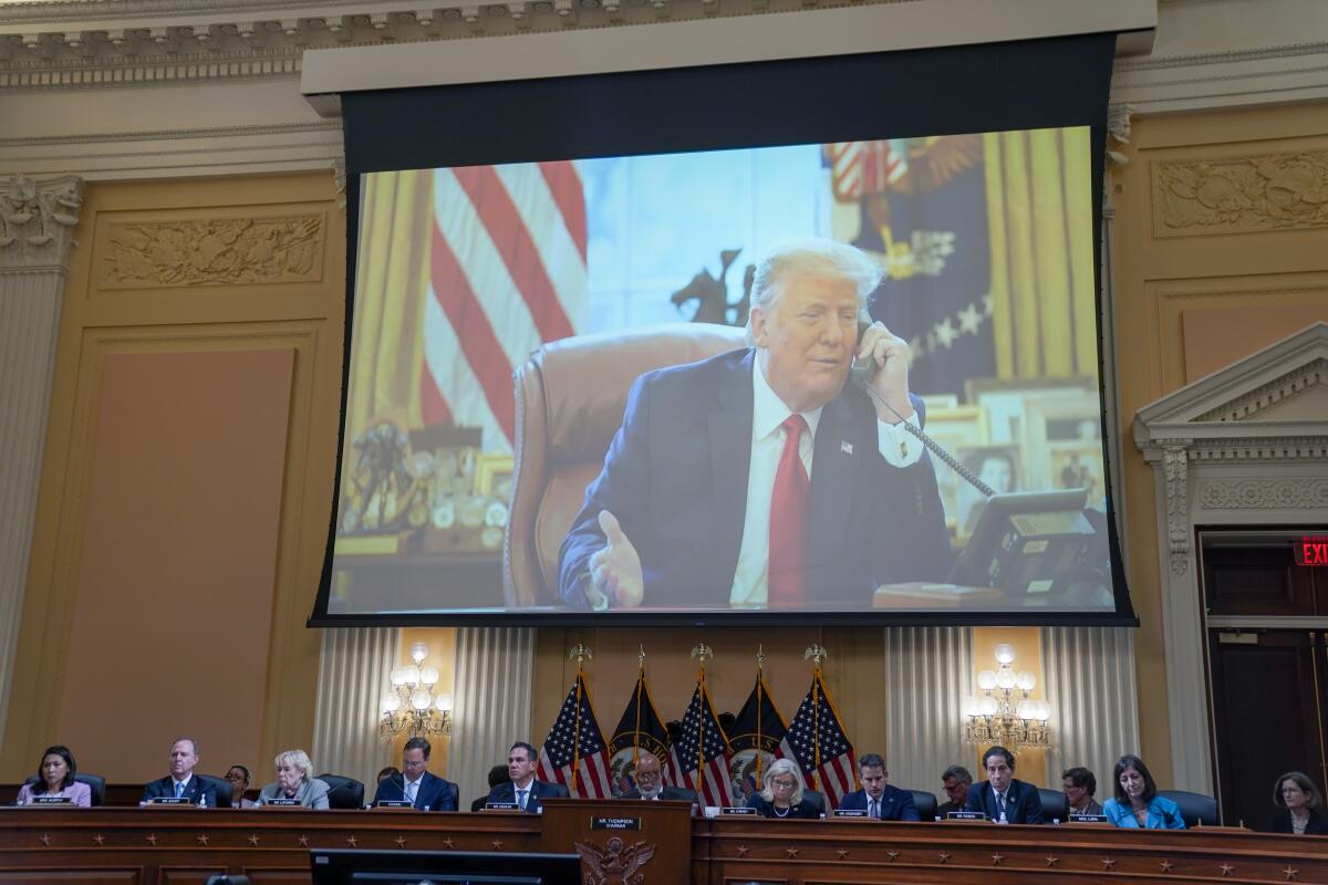 Photos of then-President Trump are shown  on a screen above dais where lawmakers are seated